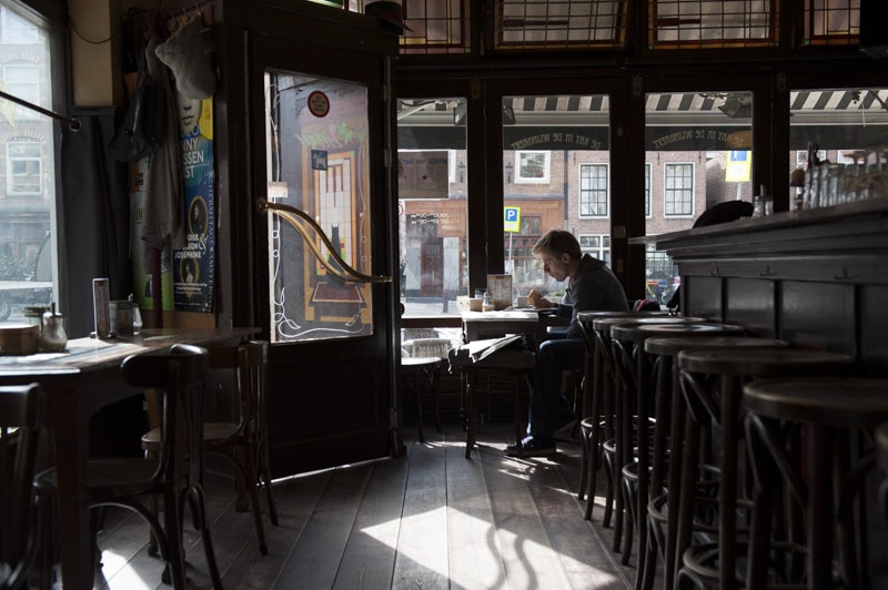 a man reading a magazine at De Kat in de Wijngaert cafe