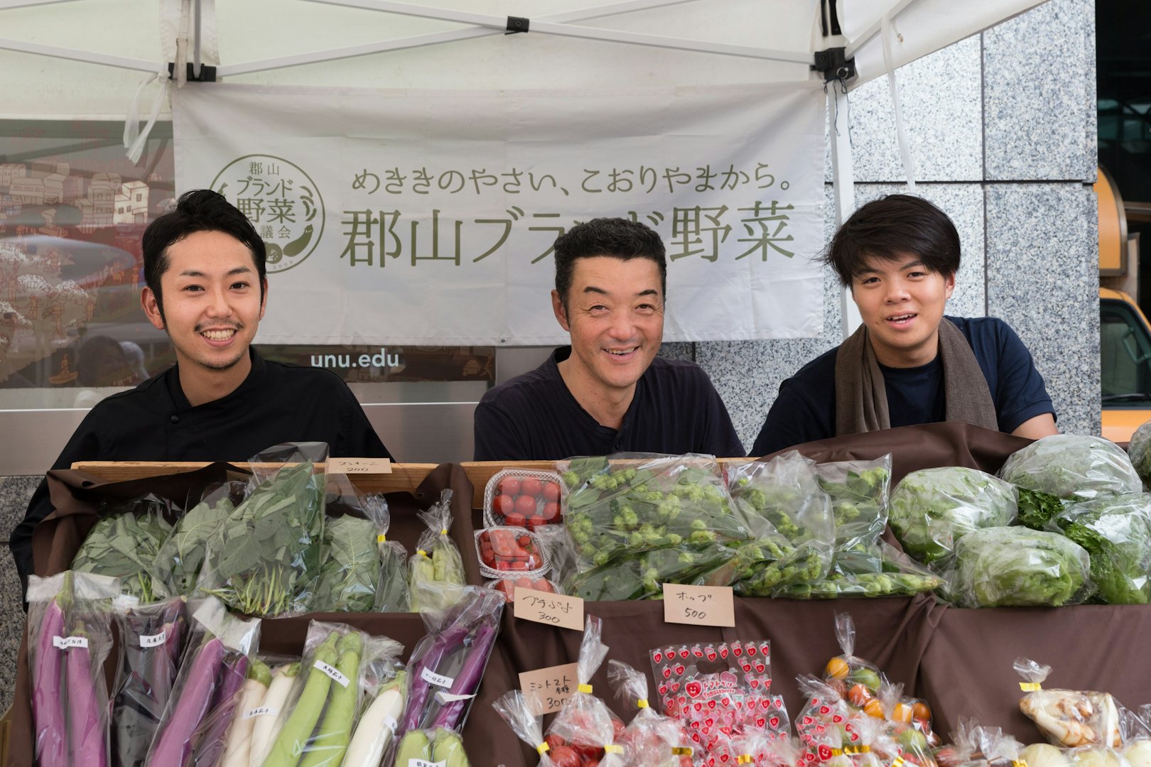 three Japanese men at a vegetable stand
