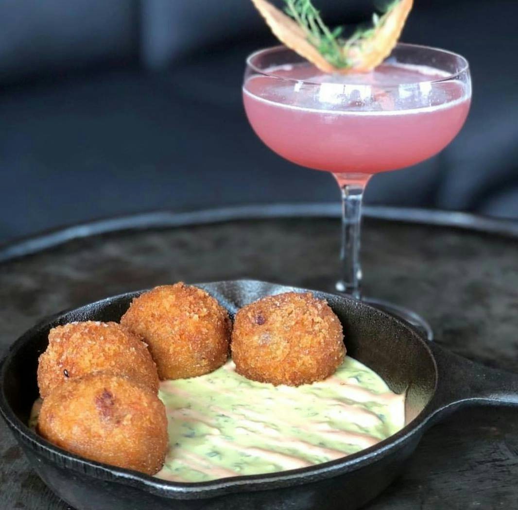 fried balls witch sauce and a pink cocktail from Beaker and Gray Miami