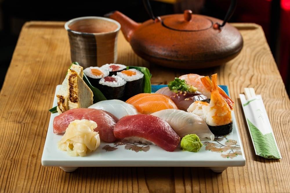 a plate full of sushi and a Japanese kettle of tea