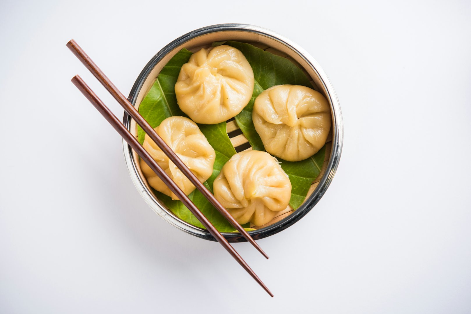 a plate of dim sum and a pair of chopsticks