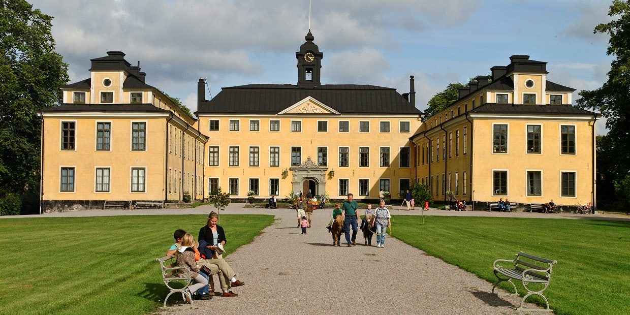 yellow exterior of the Ulriksdals Slott and people