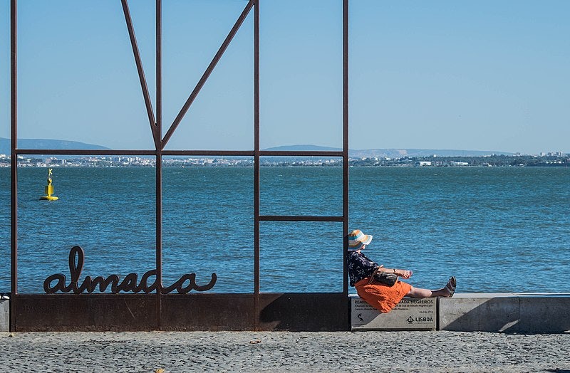 woman resting by the water at Ribeira das Naus