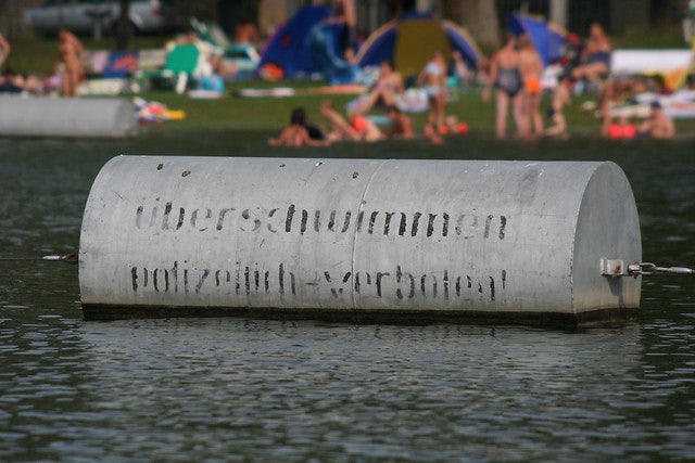 sign floating at Gänsehäufel and people in the background
