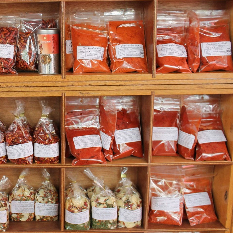 a shelf full of red and orange coloured bags with spices