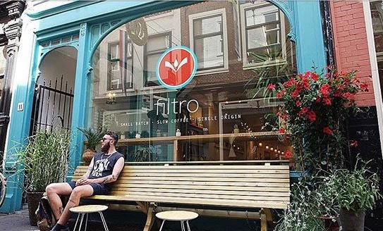 a man seated in front of Filtro coffee bar in The Hague