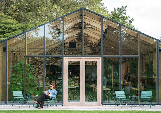 a woman sitting in front of Greens greenhouse bar