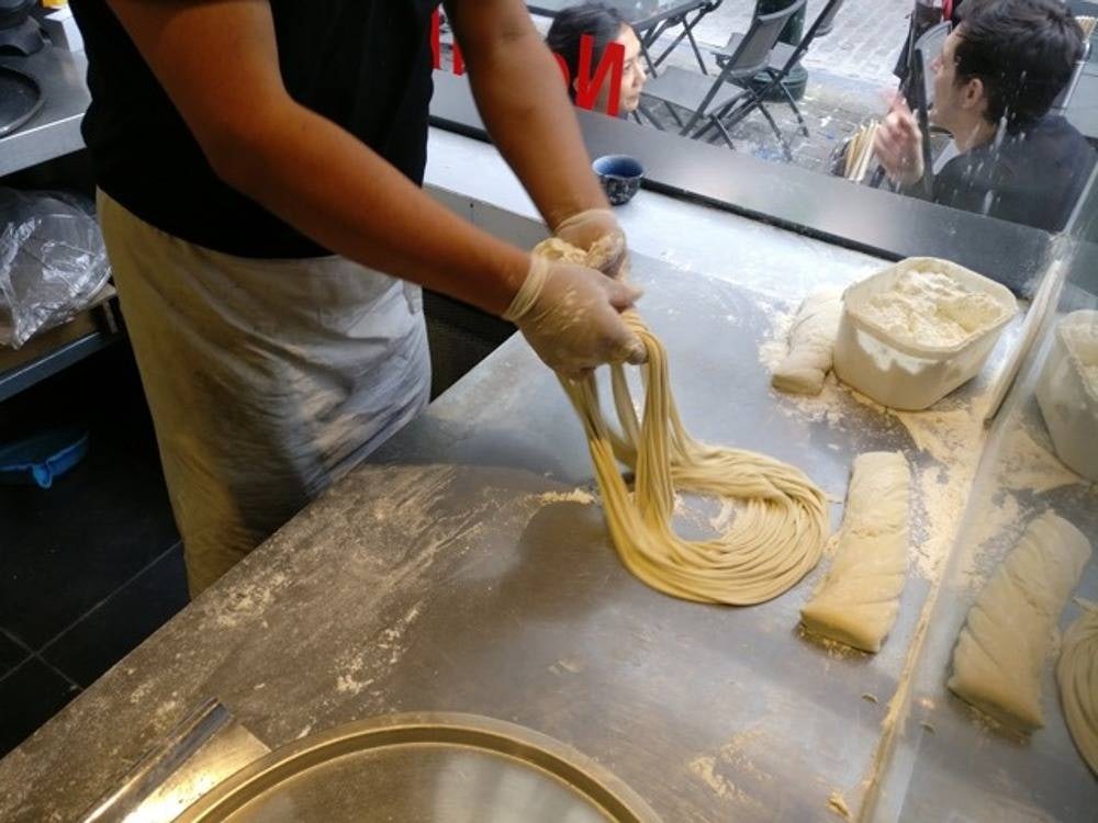 a man making fresh noodles in the kitchen of Au Bon Bol Brussels