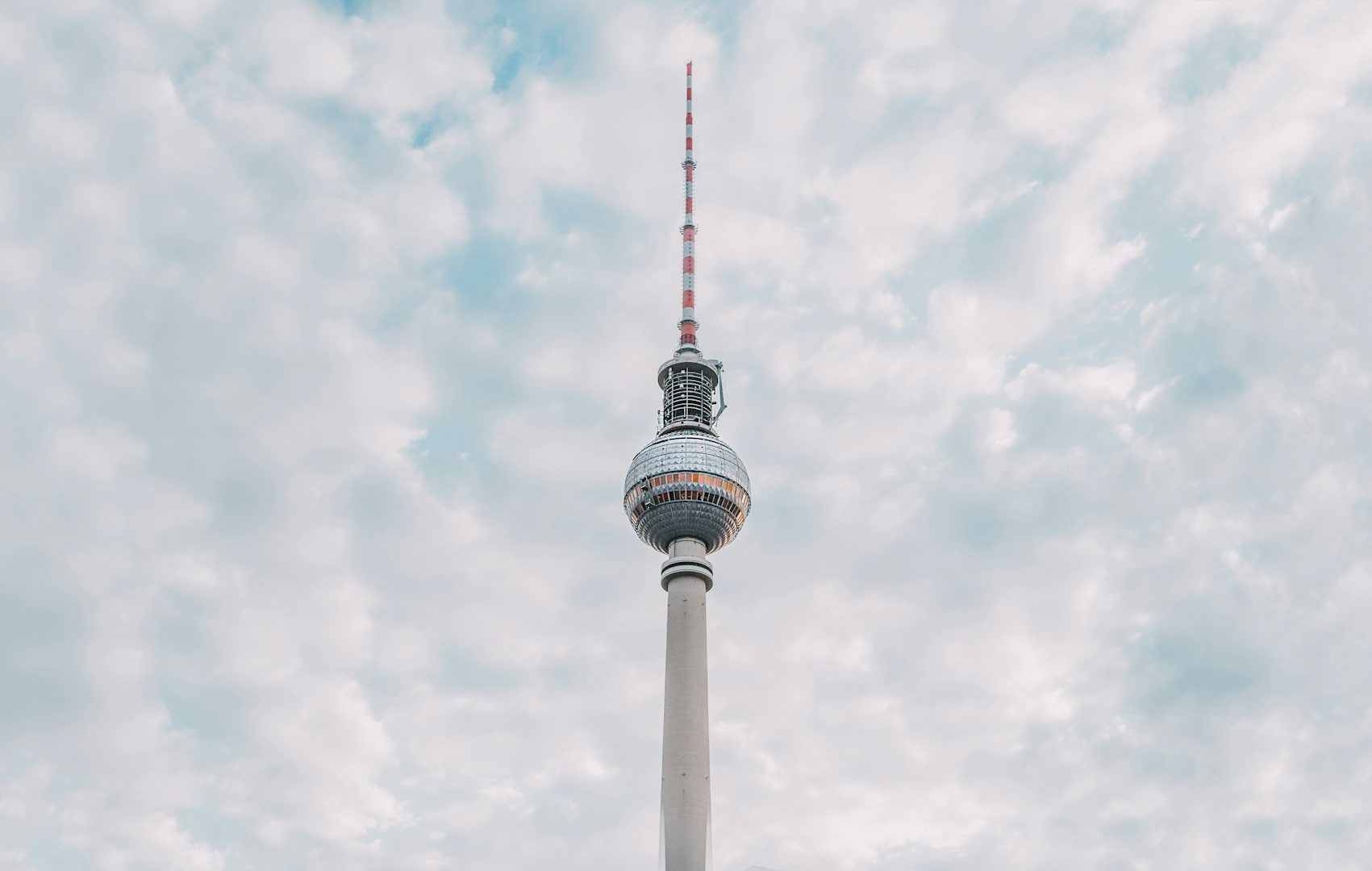 The Berlin TV tower against a light-blue cloudy sky
