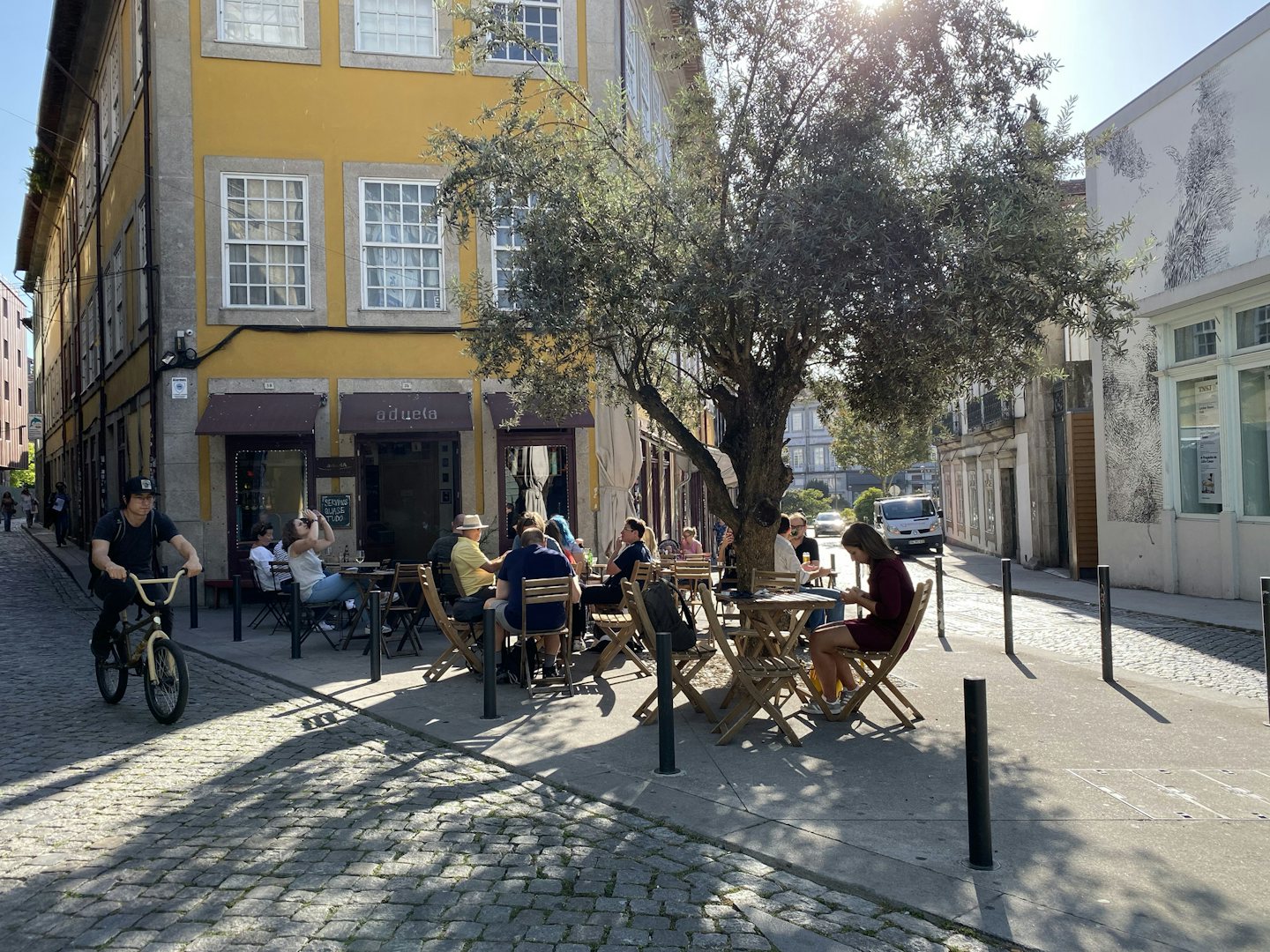 people having a drink outside on the sunny terrace of Aduela bar in Porto 