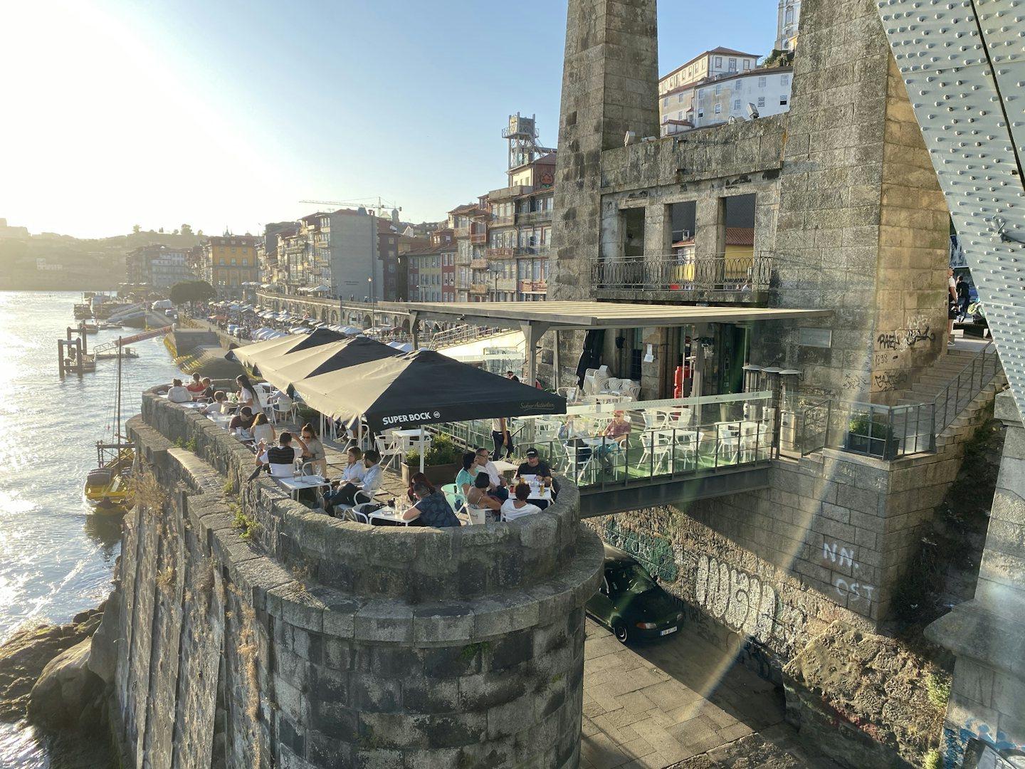 people having a drink in the sun with a view on the water at bar Ponte Pensil in Porto