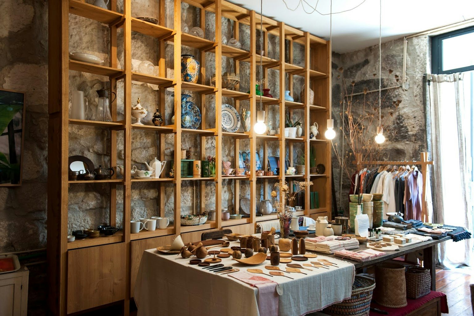 a shelf full of hand-crafted ceramics at Coração Alecrim shop in Porto