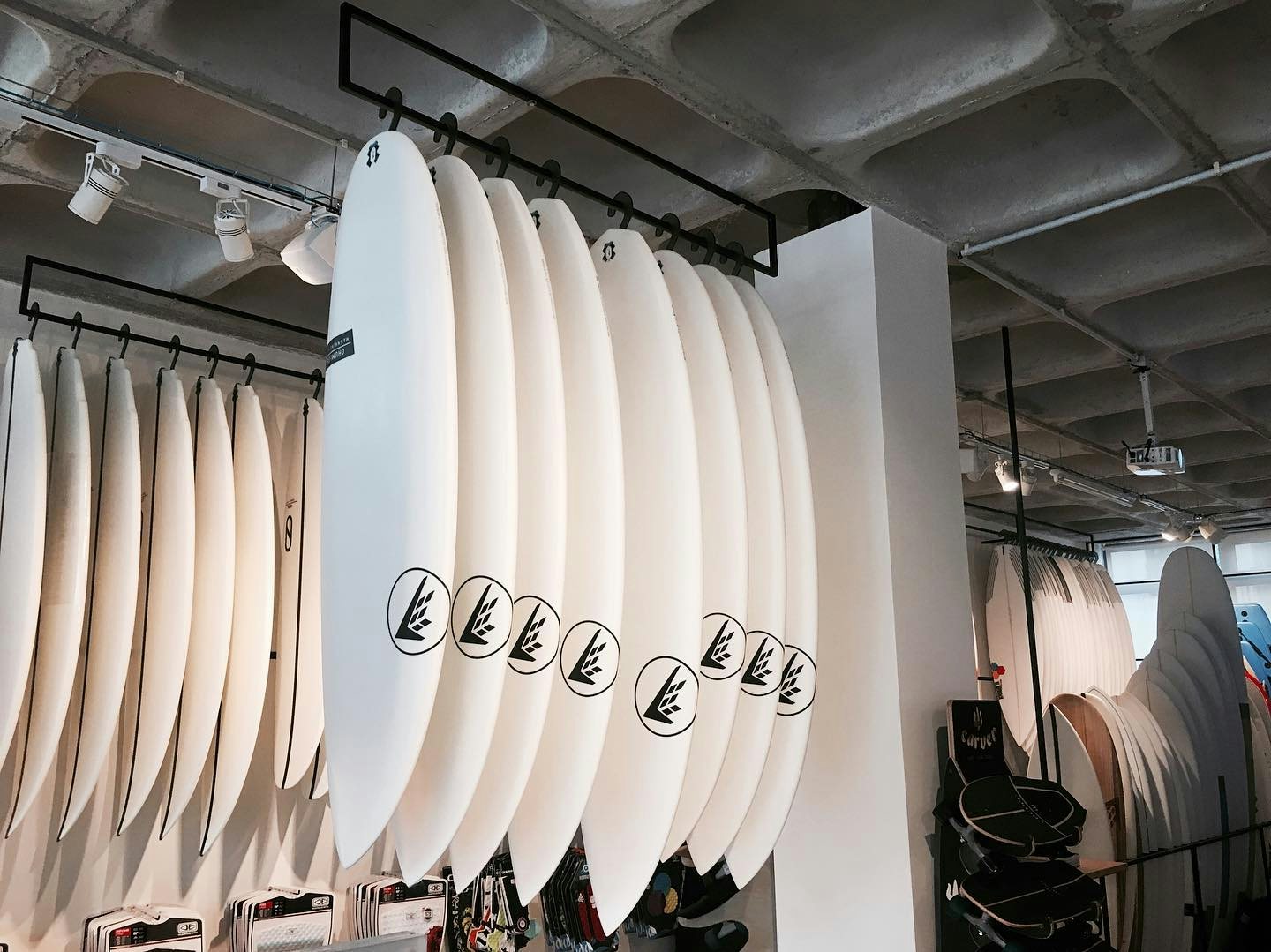 a bunch of firewire boards hanging from the ceiling at GRUA Surf Co. shop 