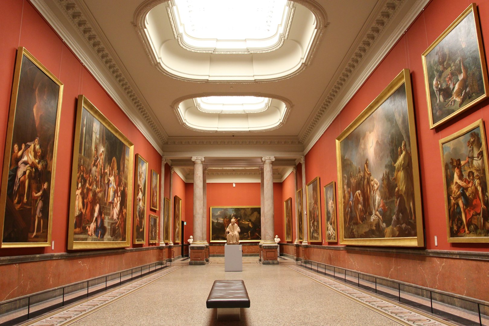 interior of the Musée de Fabre, paintings hanging at an orange pink wall