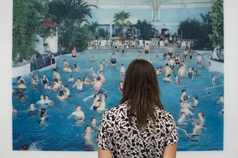 a woman admiring a photograph of a swimming pool with people swimming 