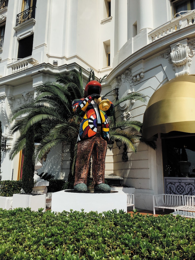 a colourful statue of a musician in front of Le Negresco hotel in Nice, France
