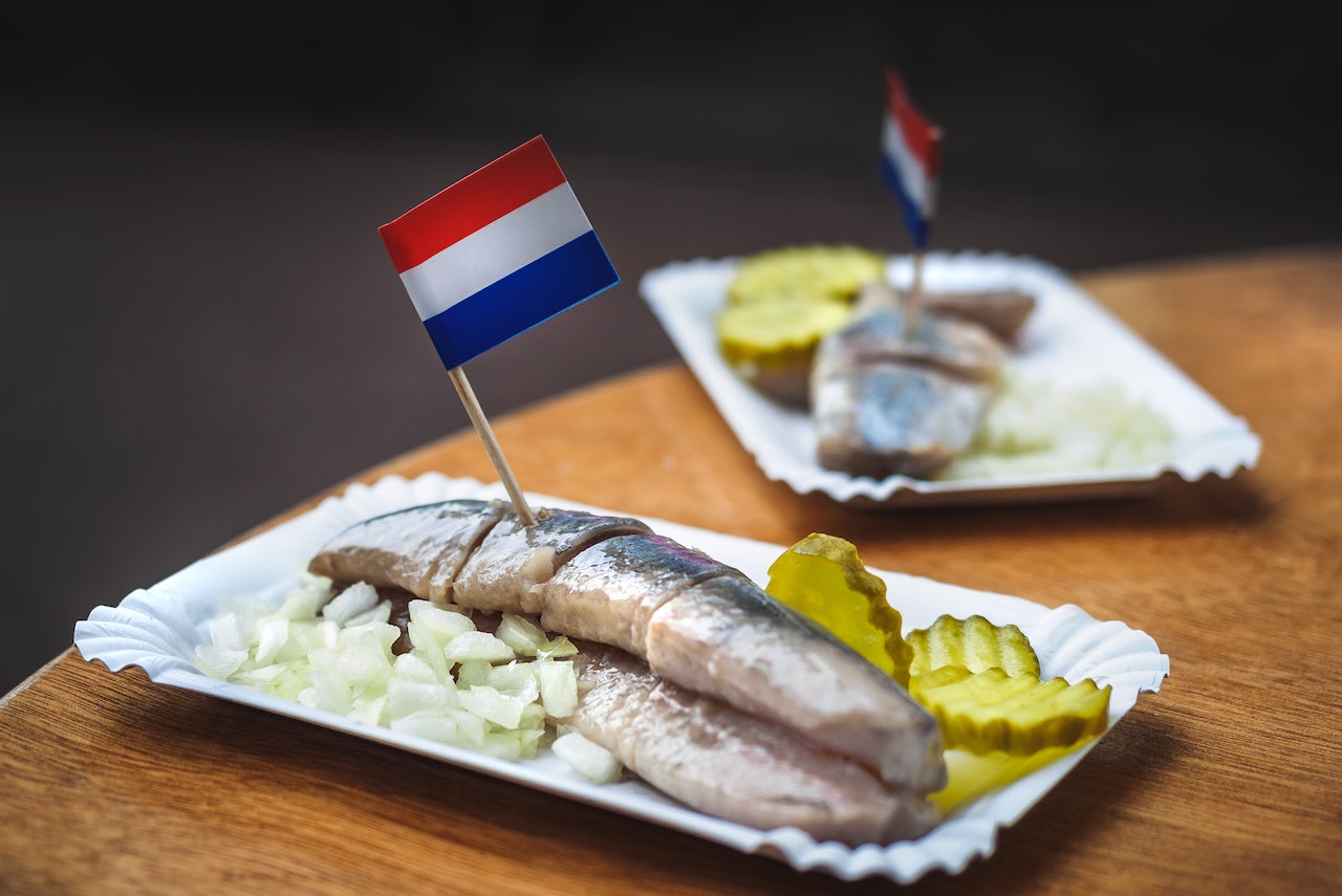 a plate of traditional Dutch-style hering with pickles and onion and a small Dutch flag