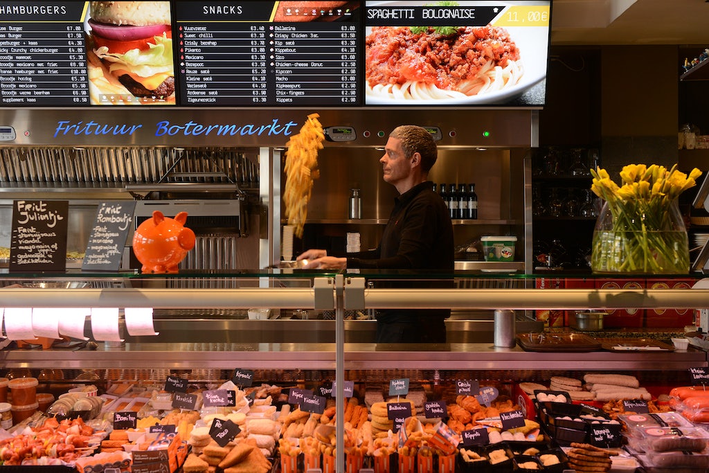 a man swinging a basket of fries at Frituur Botermarkt