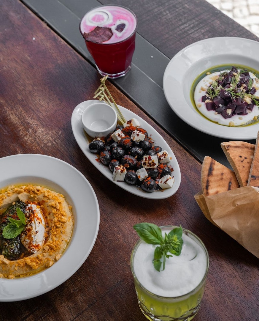 A table full of sharing dishes and two cocktails at Farès in Lisbon