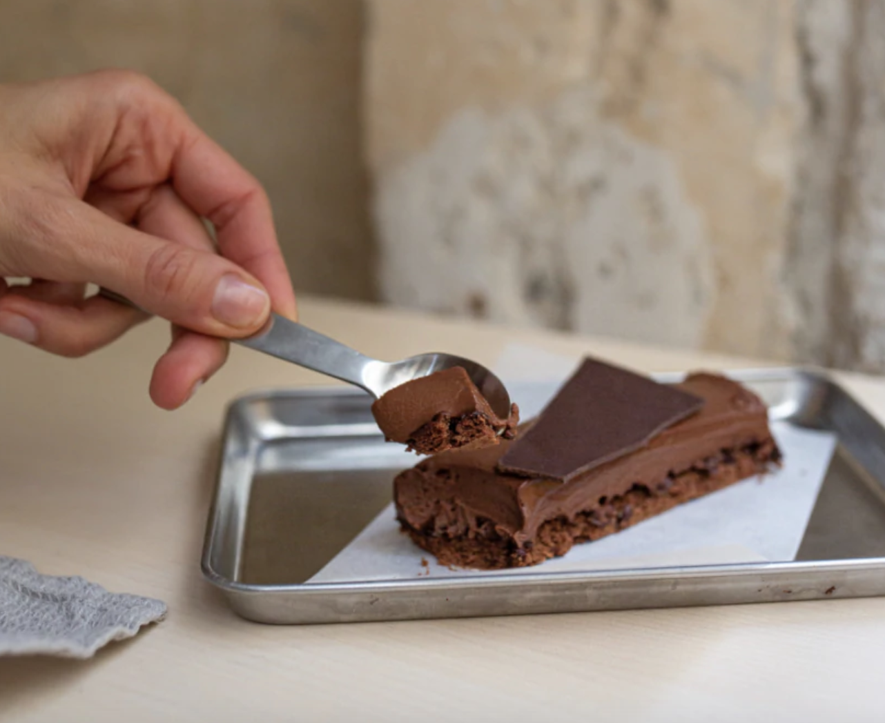 A spoon cutting into a slice of chocolate cake from Plaq in Paris