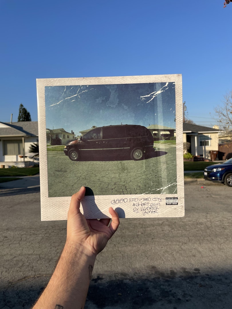 A fan holds Kendrick Lamar's Good Kid, m.A.A.d. city album in front of his childhood home in Compton