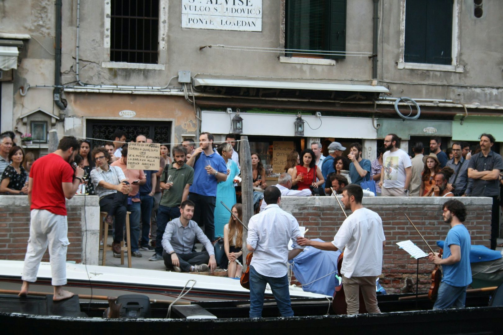 Musicians playing on a Venetian gondola in front of a bar