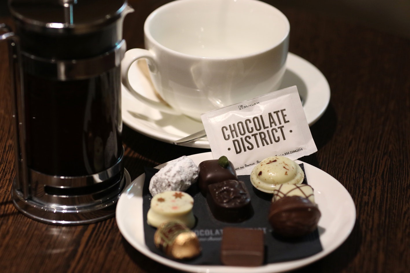 a cup of coffee and a plate of chocolates at Chocolate District