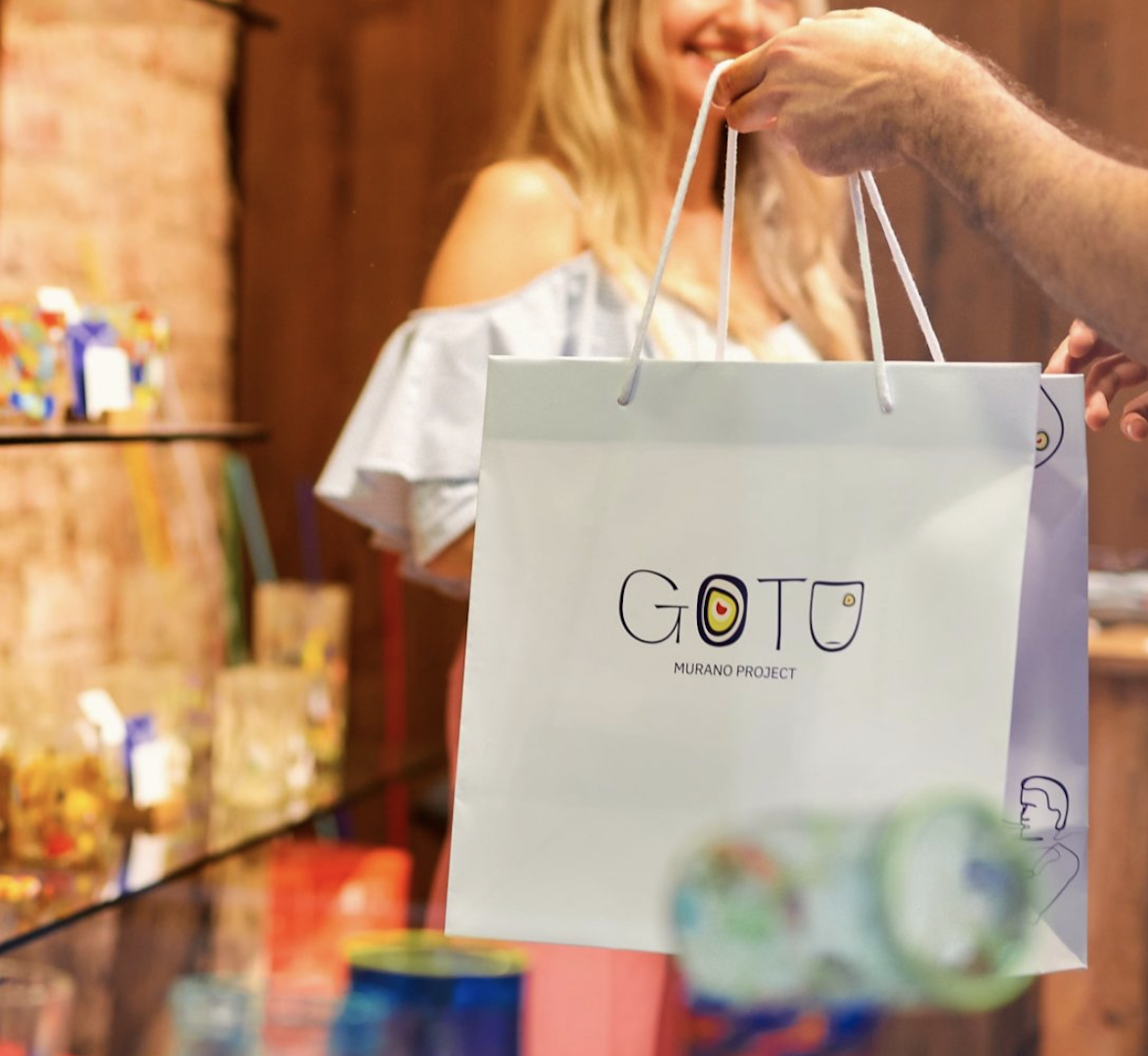 A customer holding a bag from Goto Murano Project in the shop