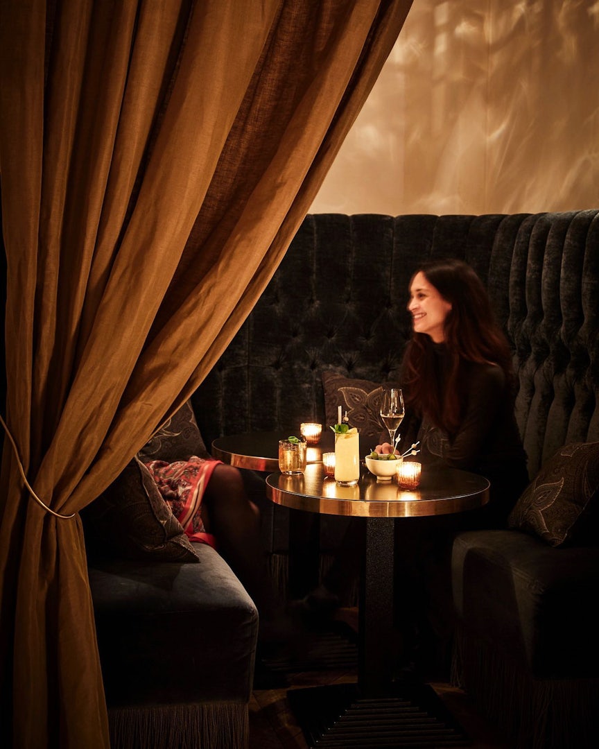 Women drinking cocktails in a booth at TATA Cocktail Bar hotel Sanders