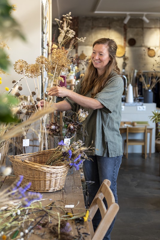 owner of Old Pine Shop arranging a flower bouquet