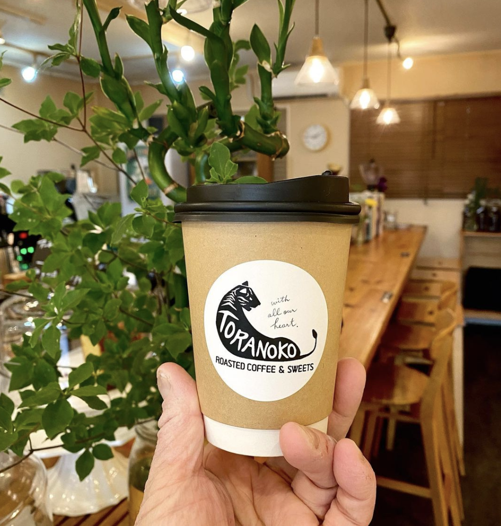 A hand holding a take-away coffee at Toranoko