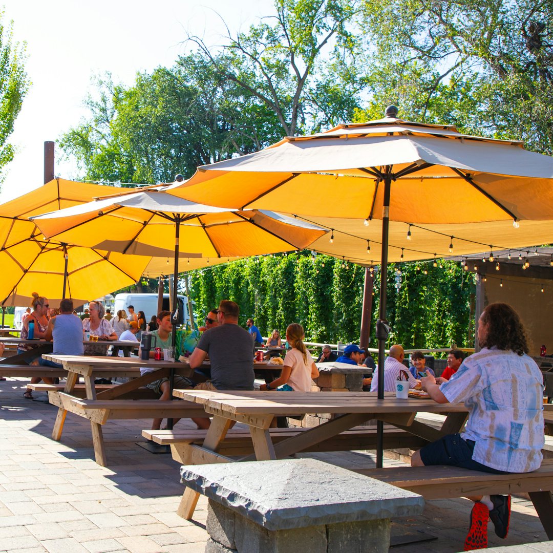 People sitting at tables under yellow parasols at Bale Breaker Taproom