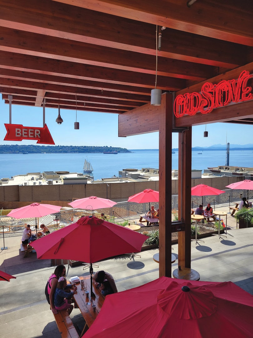 Terrace with red parasols and neon sign reading Old Stove 