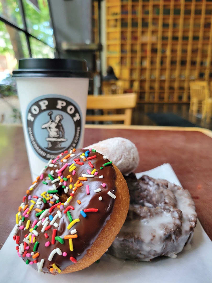 A chocolate donut with sprinkles and coffee to go at Top Pot