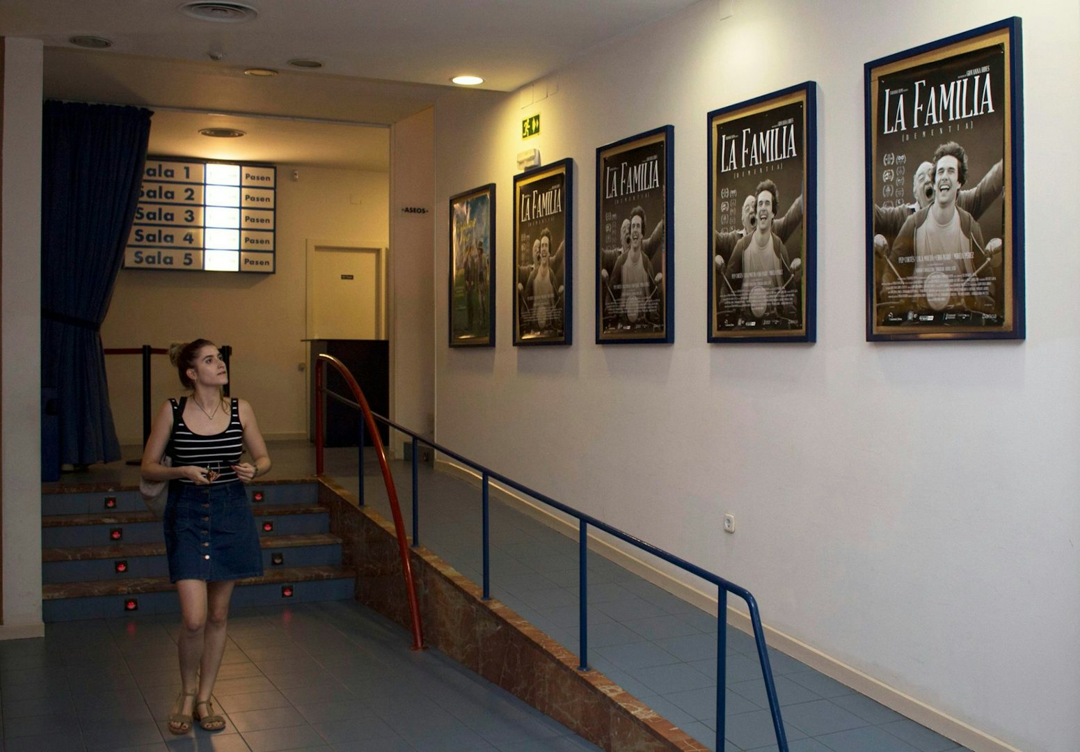 a woman walking past film posters in Cines Babel