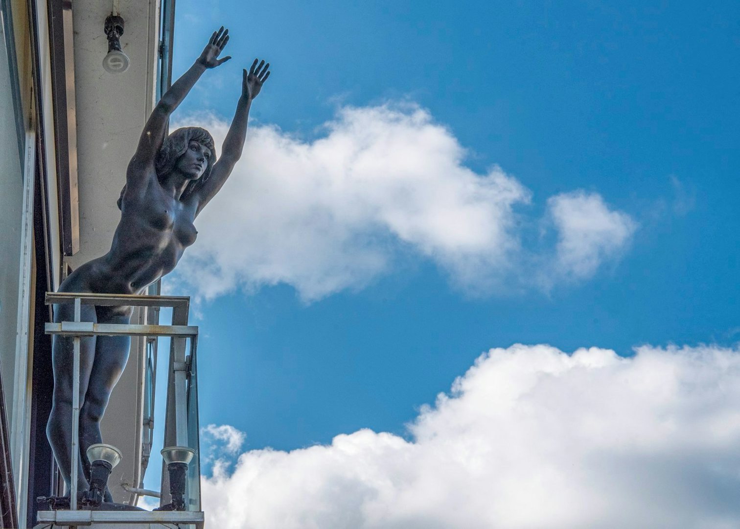 bronze statue of diving lady on top of a balcony