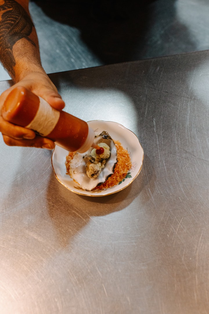 Chef dressing a plated oyster at Barbaric